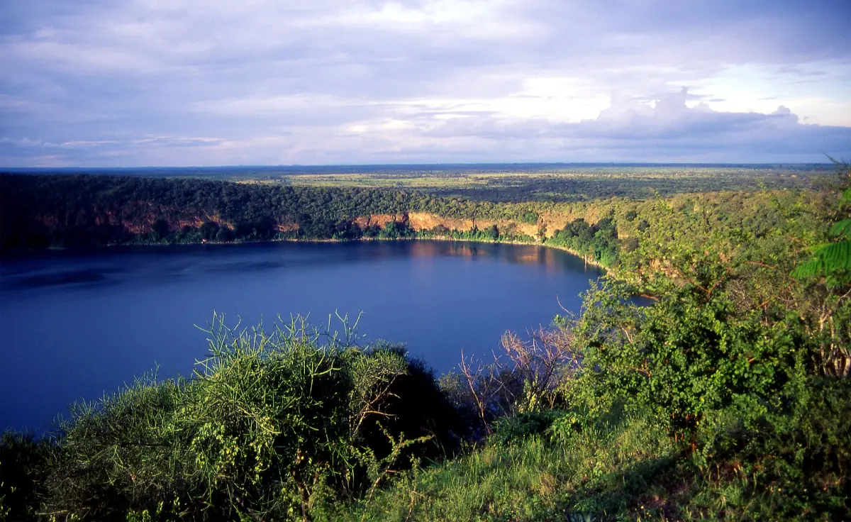 Deep blue Lake Chala surrounded by green crater walls and open plains