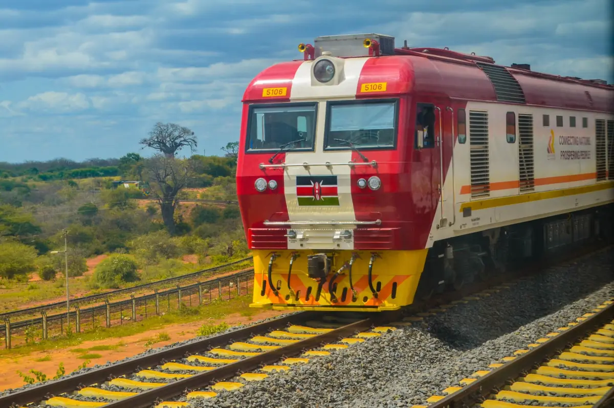 Red Madaraka Express locomotive on the Standard Gauge Railway with baobab trees