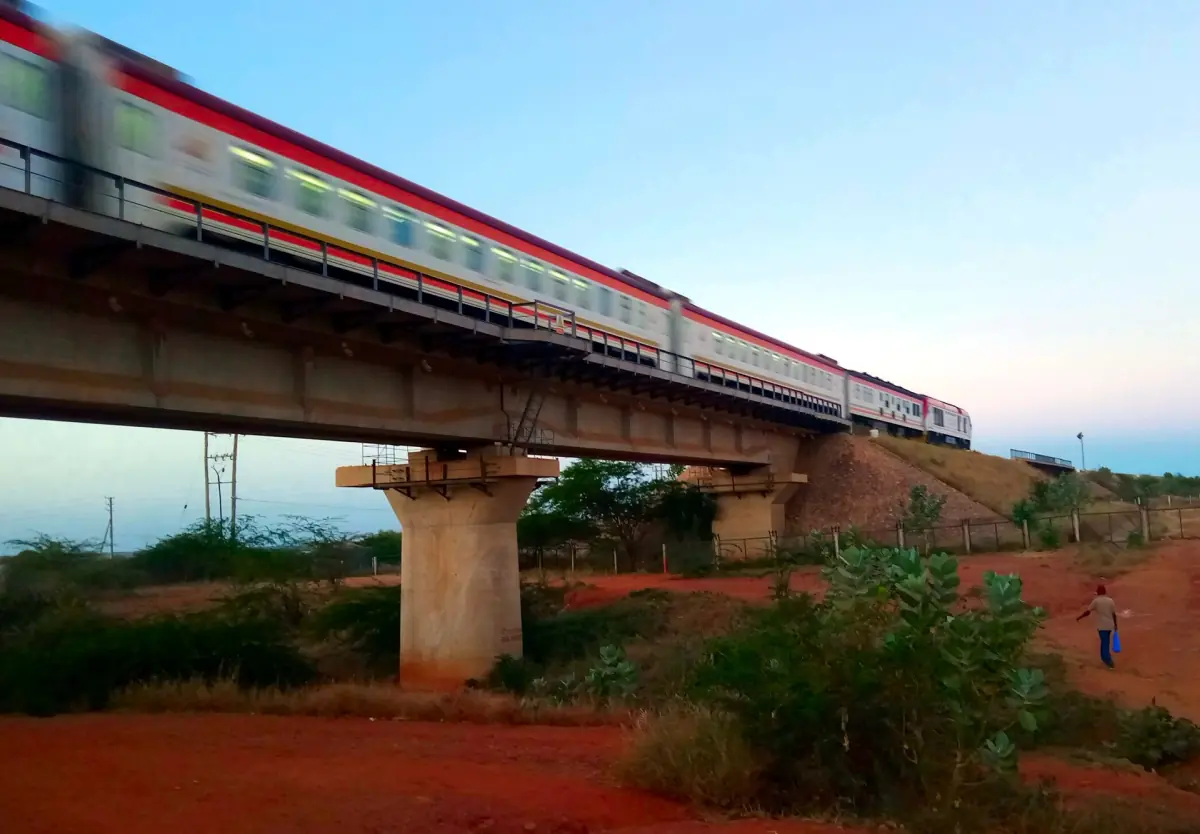 Passenger train on the Standard Gauge Railway crossing a viaduct over red soil