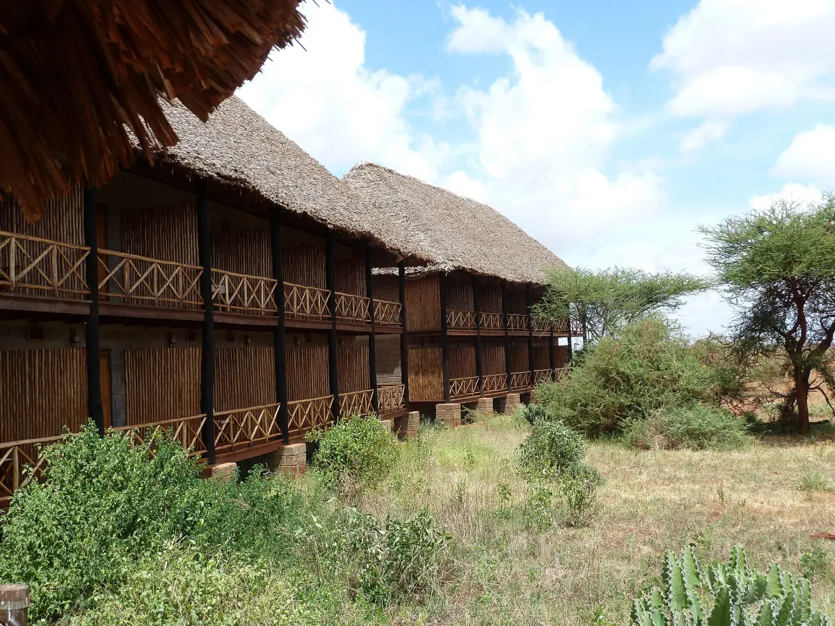 Thatched wooden lodge rooms among acacia trees at Ngutuni in Tsavo East