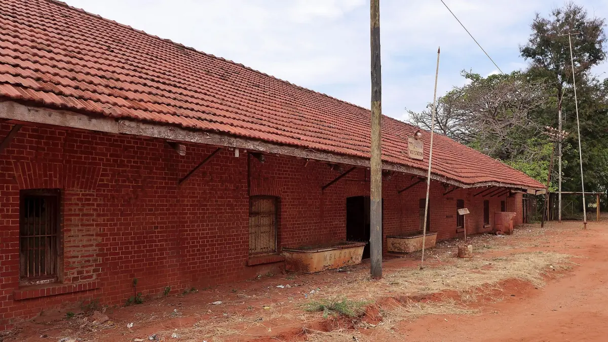 Red brick Voi railway station building with a tiled roof and dirt platform